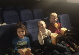 Dzieci jedzą popcorn w kinie