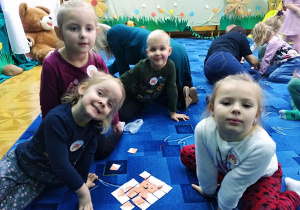 Dzieci układają puzzle - pocięte w linii prostej ilustracje misia