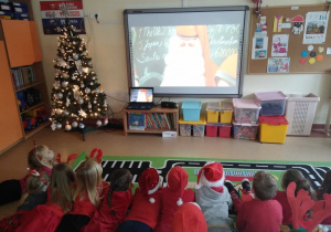 Dzieci oglądają film na tablicy multimedialnej o zwyczajach mikołajkowych