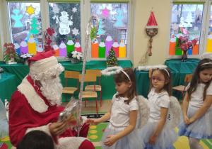 Mikołaj wręcza prezenty Aniołkom - dziewczynkom