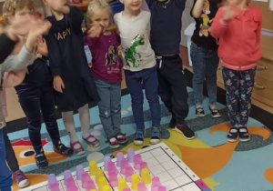 Dzieci stoją uśmiechnięte przy tablicy do kodowania - odkodowały obrazek prezentu.