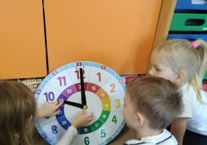 Dzieci określają na zegarze tarczowym pełne godziny