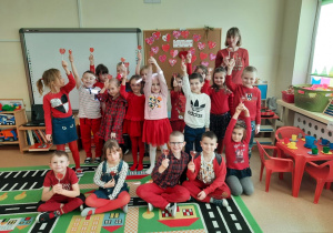 Dzieci i nauczycielka pozują do grupowego zdjęcia z lizakami w kształcie serca