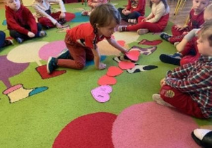Dzieci przeliczają papierowe serca na dywanie