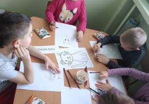 Dzieci przy stolikach samodzielnie rysują kota
