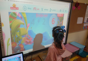 Dzieci ćwiczą umiejętności matematyczne na tablicy multimedialnej