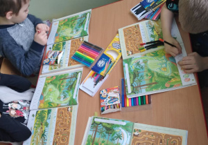 Dzieci wykonują karty pracy w książkach poświęcone dinozaurom