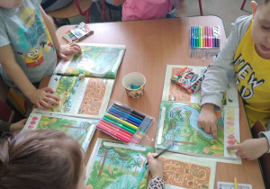Dzieci wykonują karty pracy w książkach dotyczących dinozaurów
