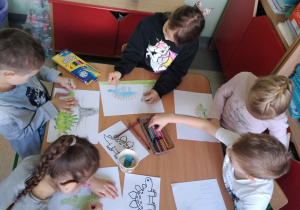 Dzieci rysują przy stolikach dinozaury