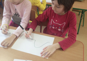 Dzieci rysują dinozaury przy stolikach
