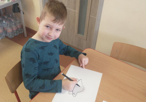 Chłopiec rysuje dinozaura według wzoru