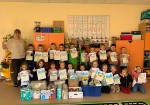 Dzieci wraz z nauczycielką pozują do zdjęcia z wykonanymi pracami i darami, które przynieśli dla najmłodszych uchodźców z Ukrainy