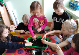 Dzieci sadzą cebulę i ziemniaki w pojemniku