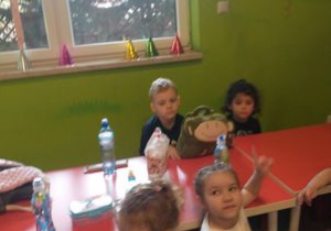 Dzieci siedzą przy stoliku i jedzą .
