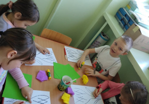 Dzieci przy stolikach wykonują krokusa - rysują po śladzie