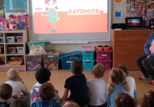 Dzieci oglądają film edukacyjny na tablicy multimedialnej na temat Święta Flagi i obchodów Konstytucji 3-go Maja