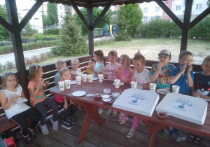 Dzieci jedzą pizzę na kolację w przedszkolnej altanie