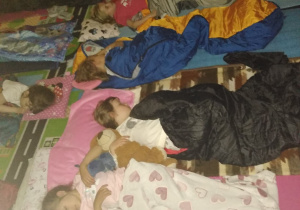 Dzieci śpią w śpiworach w przedszkolnej sali