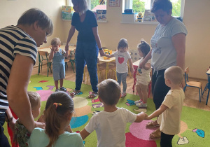 Dzieci wraz z pracownikami przedszkola biorą udział w zabawach kołowych przy muzyce