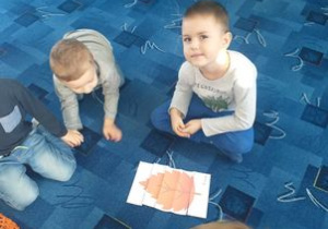 Chłopcy układają puzzle liści.