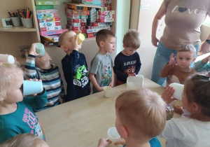 Dzieci piją z kubków koktajl bananowy.