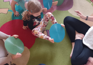 Dzieci przenoszą krążek gimnastyczny stopami