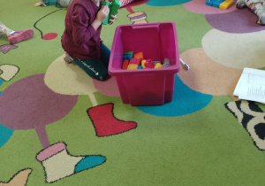 Dziewczynka wybiera z pudełka klocki w określonym kolorze