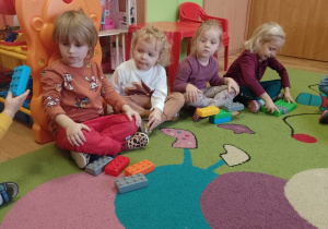 Dzieci siedzą w kole z przeliczonymi przez siebie klockami