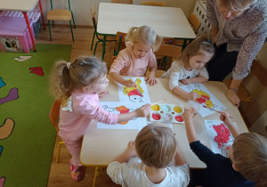 Dzieci wypełniają farbami konkury Kubusia Puchatka