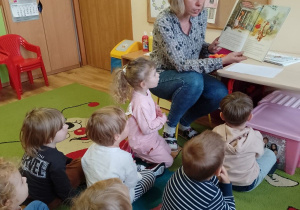 Nauczycielka czyta dzieciom fragment książki o przygodach Kubusia Puchatka