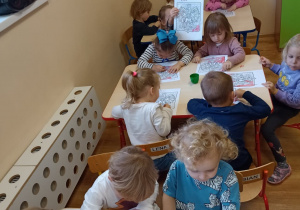 Dzieci kolorują czerwoną kredką godło Polski