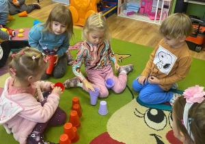 Dzieci układają kubeczki w określonych kolorach piętrowo