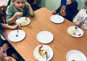 Dzieci jedzą wykonaną samodzielnie sałatkę.