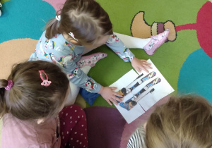 Dzieci w grupach układają puzzle - pocięty na trzy części obrazek przedstawiający narty