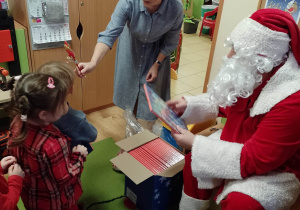 Mikołaj wraz z panią dyrektor wręczają dzieciom upominki