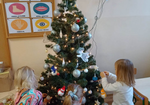 Dzieci dekorują świąteczne drzewko bombkami