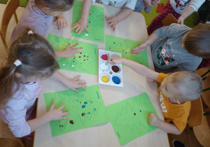 Dzieci malują paluszkami zamoczonymi w farbie bombki na choince