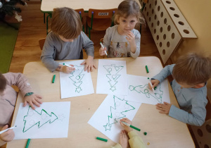 Dzieci rysują po śladzie mazakiem kształt choinki
