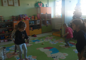 dzieci na dywanie ćwiczą stopy z woreczkami gimnastycznymi