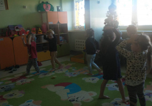 dzieci ćwiczą na dywanie z woreczkami gimnastycznymi na głowie