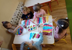 Dzieci malują kartkę papieru różnymi kolorami, z której później robić będą wachlarze
