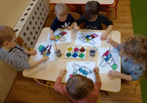 Chłopcy wypełniają farbami kontury obrazka przedstawiającego dzwonki chromatyczne