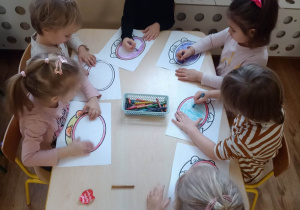Dzieci wypełniają kredkami kontury obrazka przedstawiającego tamburyn