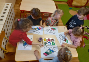 Dziewczynki wypełniają farbami kontury obrazka przedstawiającego dzwonki chromatyczne