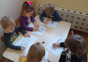 Dzieci wykonują pracę grafomotoryczną - rysują mazakiem po śladzie