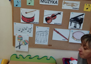Nauczycielka przy tablicy tematycznej omawia wygląd poszczególnych instrumentów muzycznych