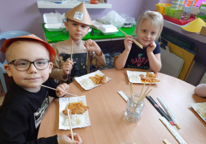 dzieci w czapkach chińskich jedzą chińskie dania