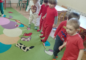 Dzieci ubrane w stroje w czerwonym kolorze wykonują ćwiczenia gimnastyczne