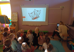 Dzieci oglądają prezentacje multimedialną na temat kotów będących pod opieką Stowarzyszenia niKOTyna