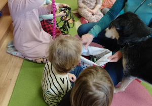 Dziewczynka pokazuje dzieciom ulubioną zabawkę pieska